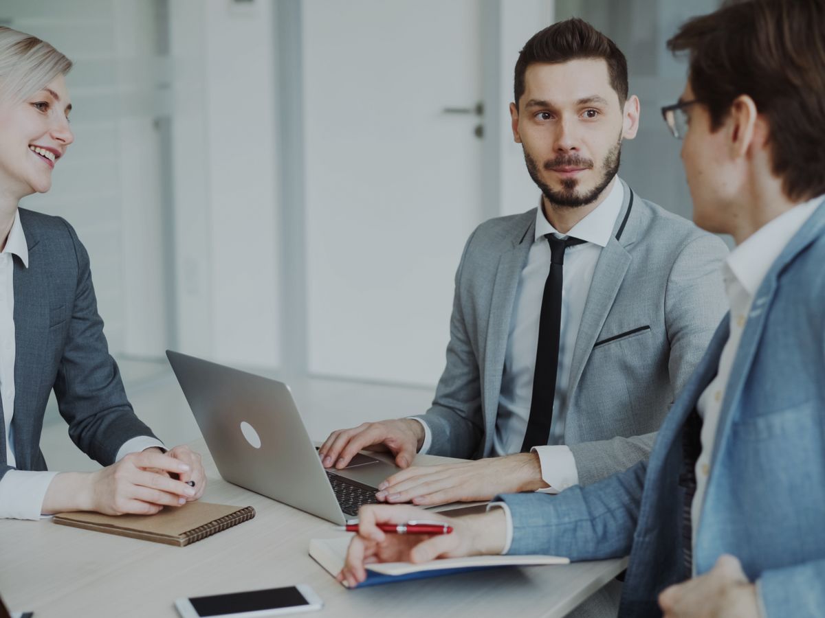 Business professionals discussing a project around a laptop